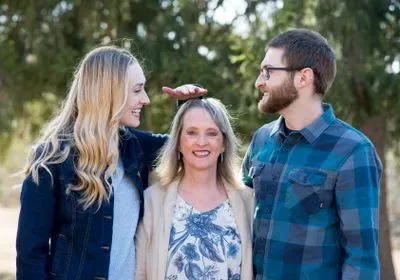 a smiling woman standing between a much taller man and woman a smiling woman standing between a much taller man and woman